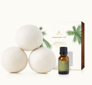 Three white wool dryer balls next to a bottle of Frasier Fir laundry fragrance oil and its packaging box.