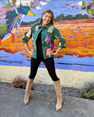 Woman posing in front of a colorful mural wearing a patterned green jacket.