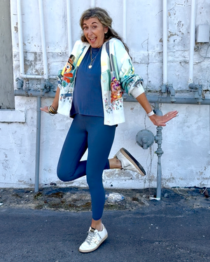 Woman posing outdoors against a white wall with pipes.