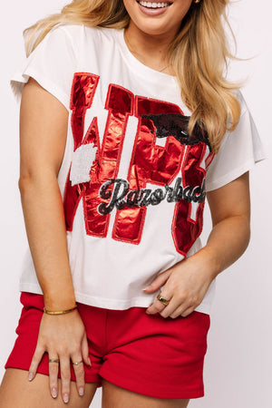 Person wearing a white t-shirt with red and black text design and red shorts on a white background