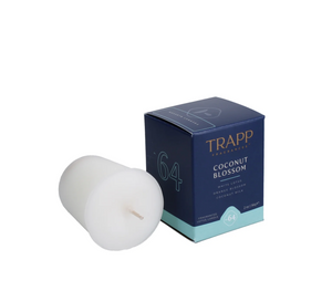 A white votive candle with a clear wax is displayed in front of its blue and green packaging box labeled 'Trapp No. 64 Coconut Blossom'.