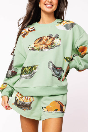Woman wearing a green sweatshirt and shorts set with food print design on a white background