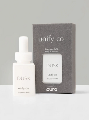 A bottle of Dusk Home Fragrance Diffuser Oil by unify co., with a gray packaging box labeled 'PURA'.